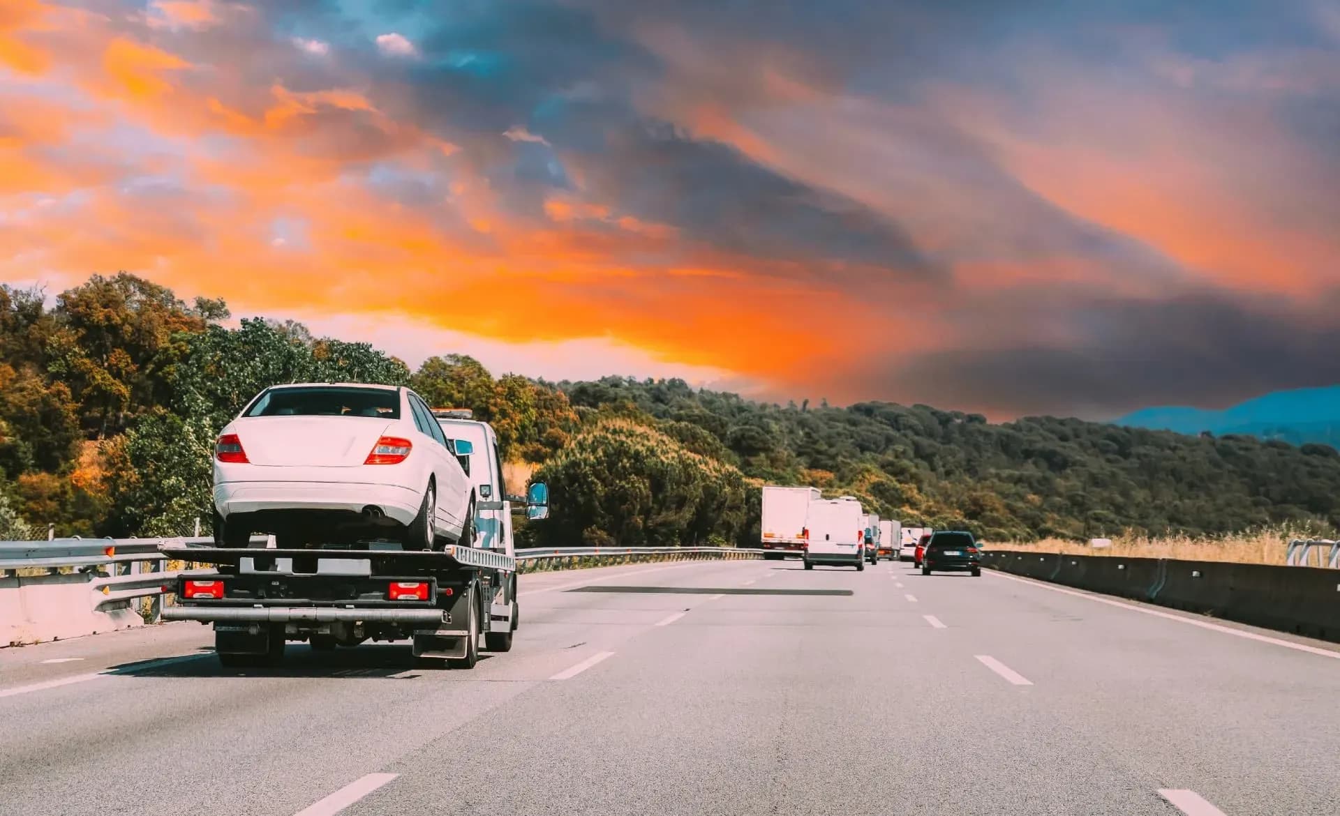 Tow truck assisting a vehicle on a road at sunset in Finland